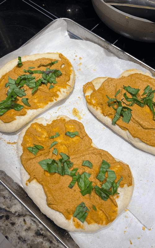 remove the flatbread from teh oven and spread the humus on top before baking again